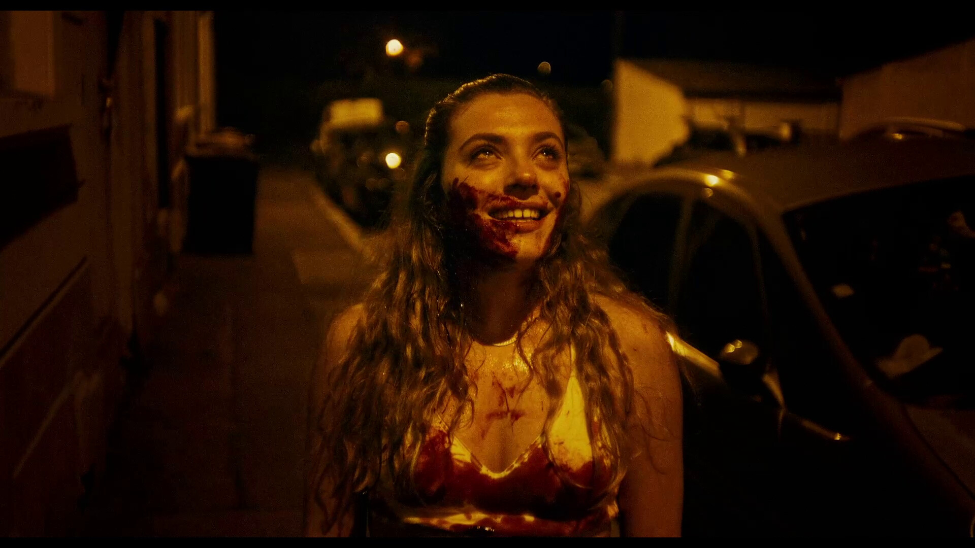 A young woman stares up with a crazed look on her bloody face